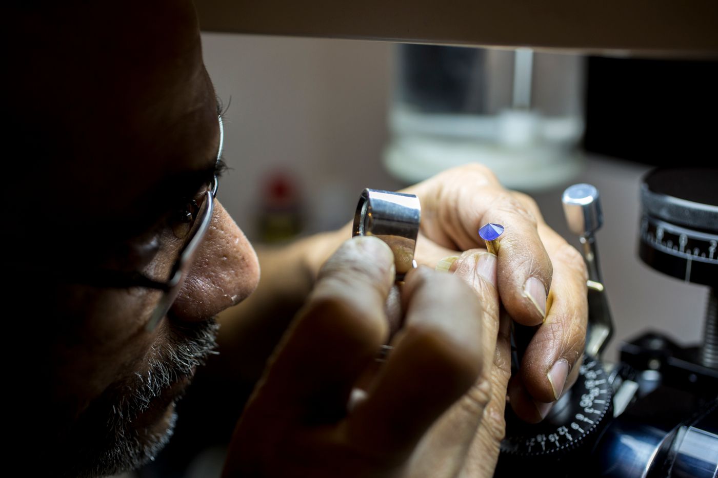 A gemmologist studying a stone through a loupe