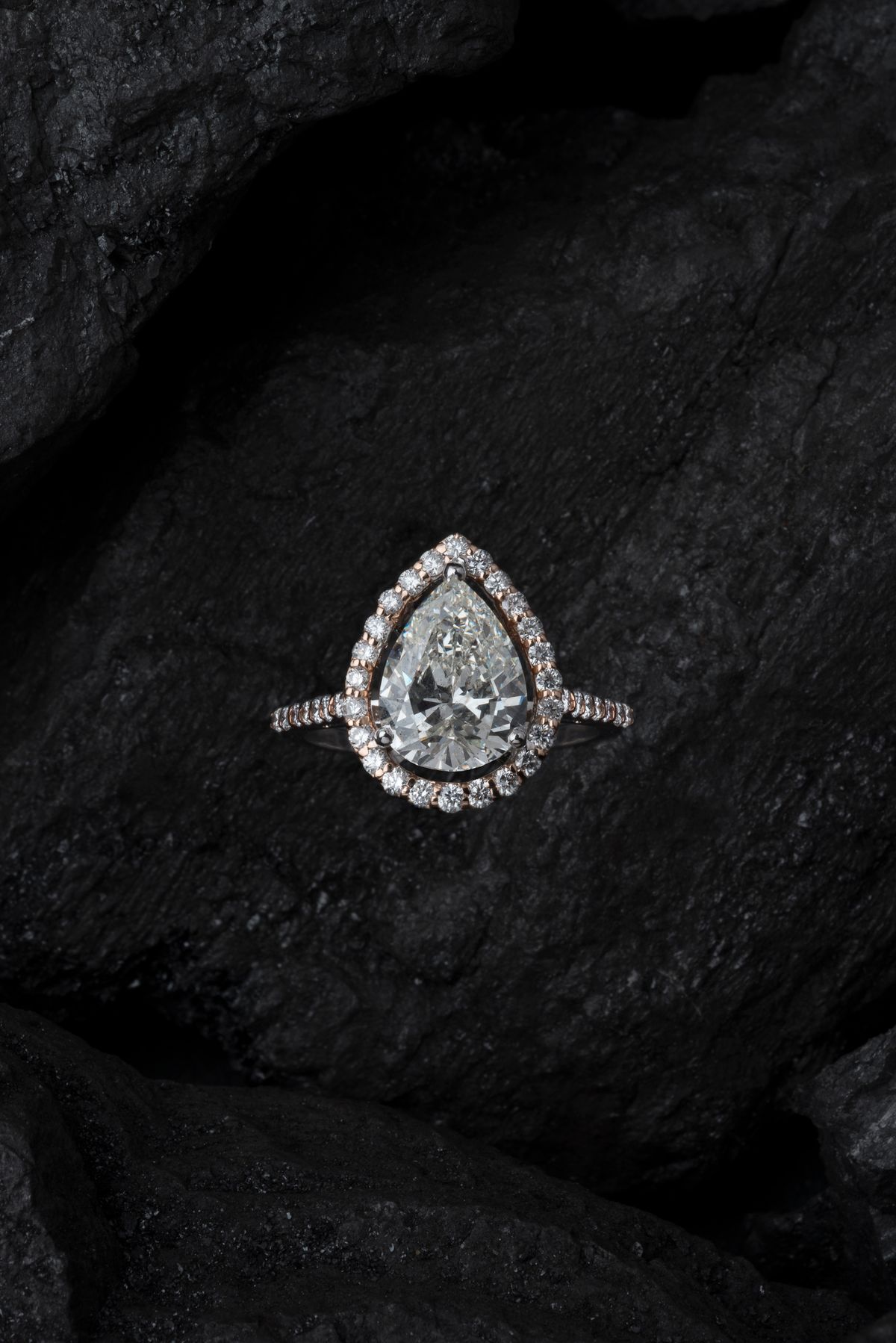 A pear-shaped diamond ring resting on dark stone